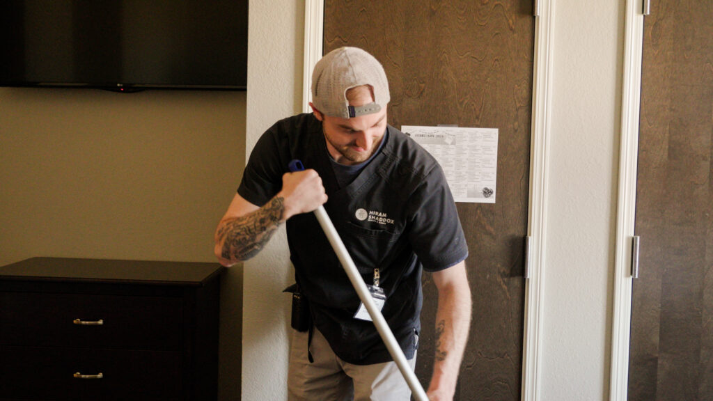 A staff worker cleaning a room at a skilled nursing facility